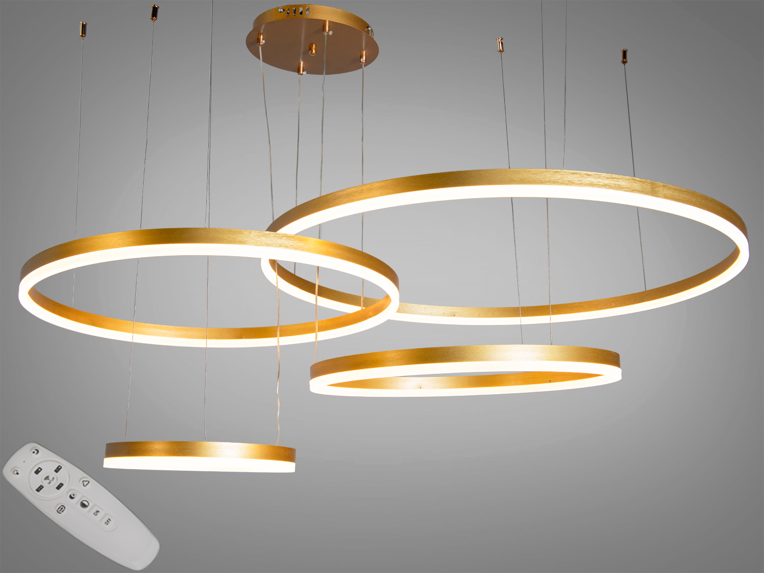Підвісний світильник з пультом дистанційного керування, що дозволяє регулювати освітлення, має три золоті кільця.