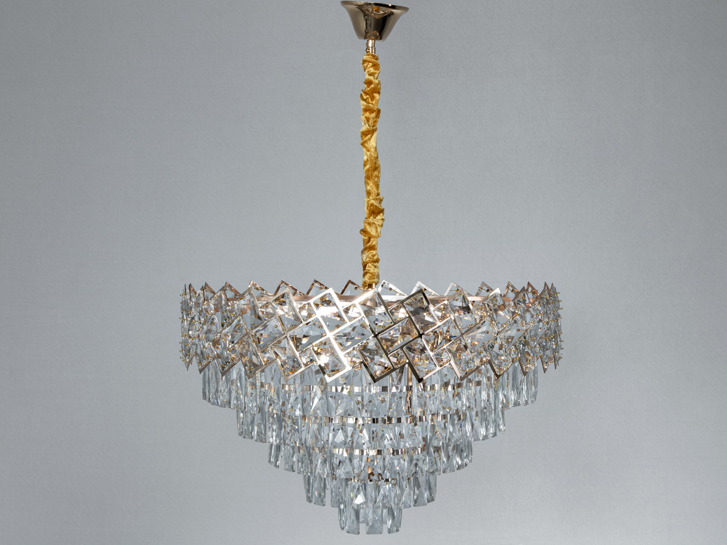 Елегантна люстра з кришталю з золотистими акцентами, підвішена на декоративному шнурі, підходить для спальні.