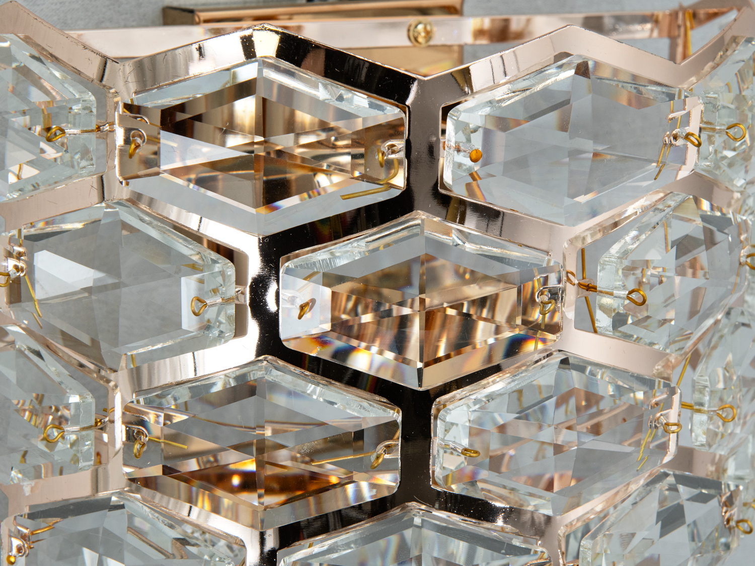 Крупний план кришталевих елементів настінного світильника, що відбивають світло. Гексагональна форма надає унікальності.