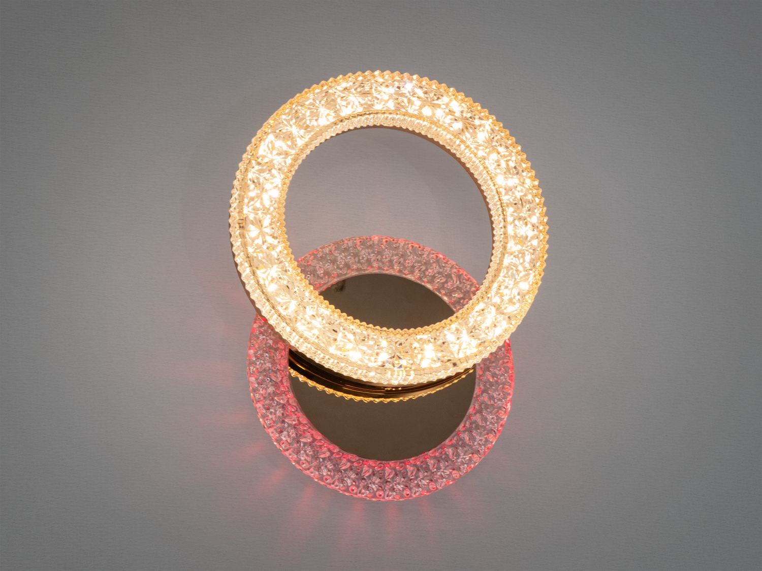 Настінний світильник у формі двох кілець з теплим жовтим світлом, підходить для сучасного інтер’єру, створює затишну атмосферу.