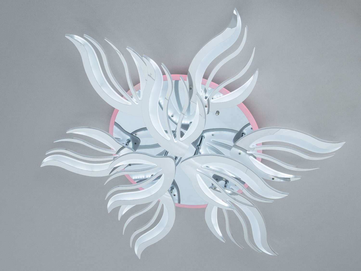 Стельовий світильник з хвилястими білими елементами, рожеве підсвічування додає м’якість.