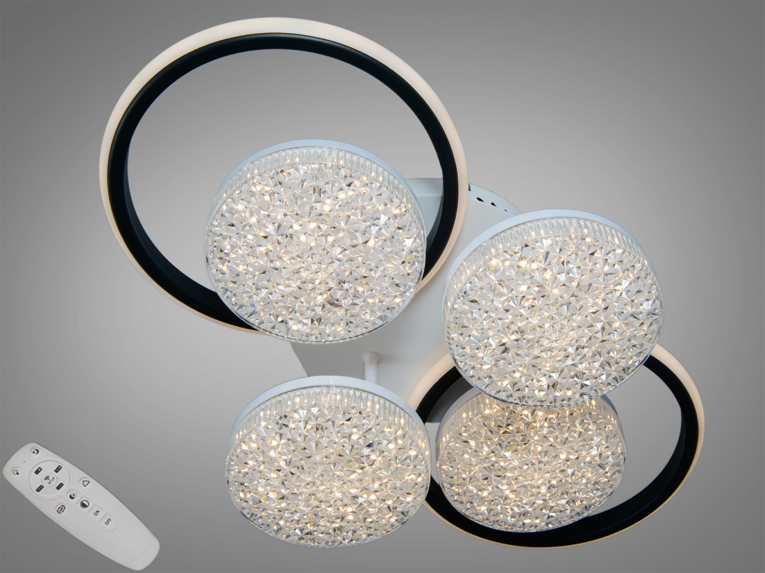 Світильник з пультом дистанційного керування, має чотири LED-елементи в чорних кільцях, підходить для сучасних інтер’єрів.