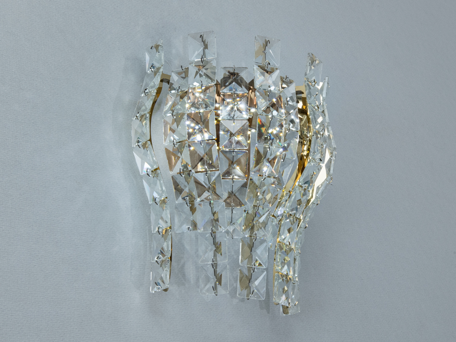 Настінний світильник з кришталю, що має золотисті акценти, додає розкішного вигляду. Ідеальний для вітальні або спальні.