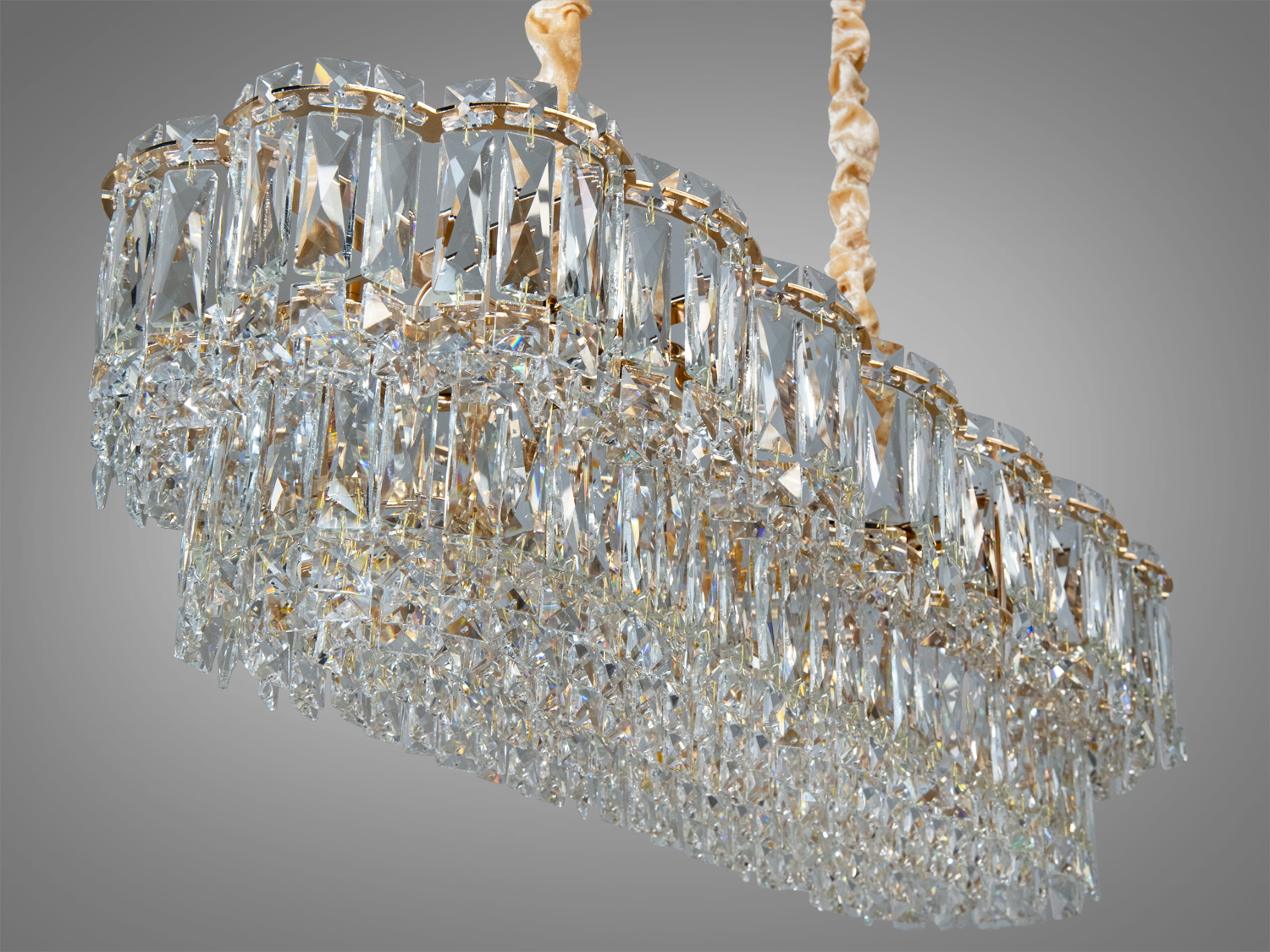 Кришталевий світильник з багатошаровими підвісками, підвішений на шнурах з тканини, додає вишуканості класичному декору.