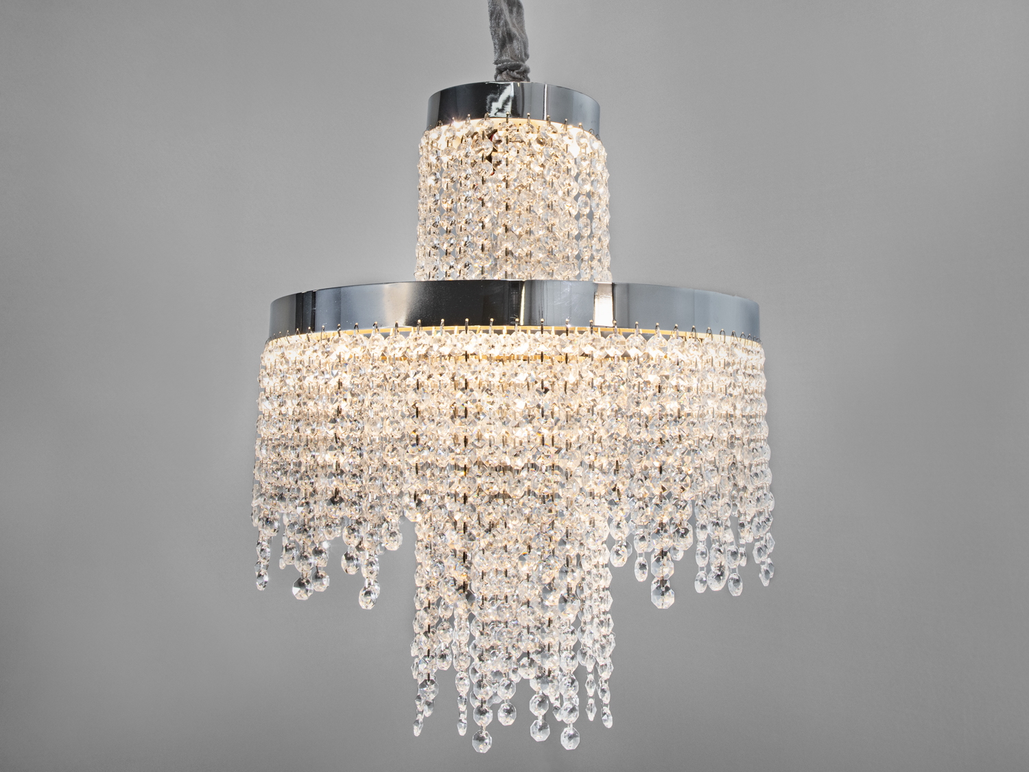 Люстра з кришталевими підвісками, два яруси, хромована основа, відбиває світло, ідеальна для класичного інтер’єру.