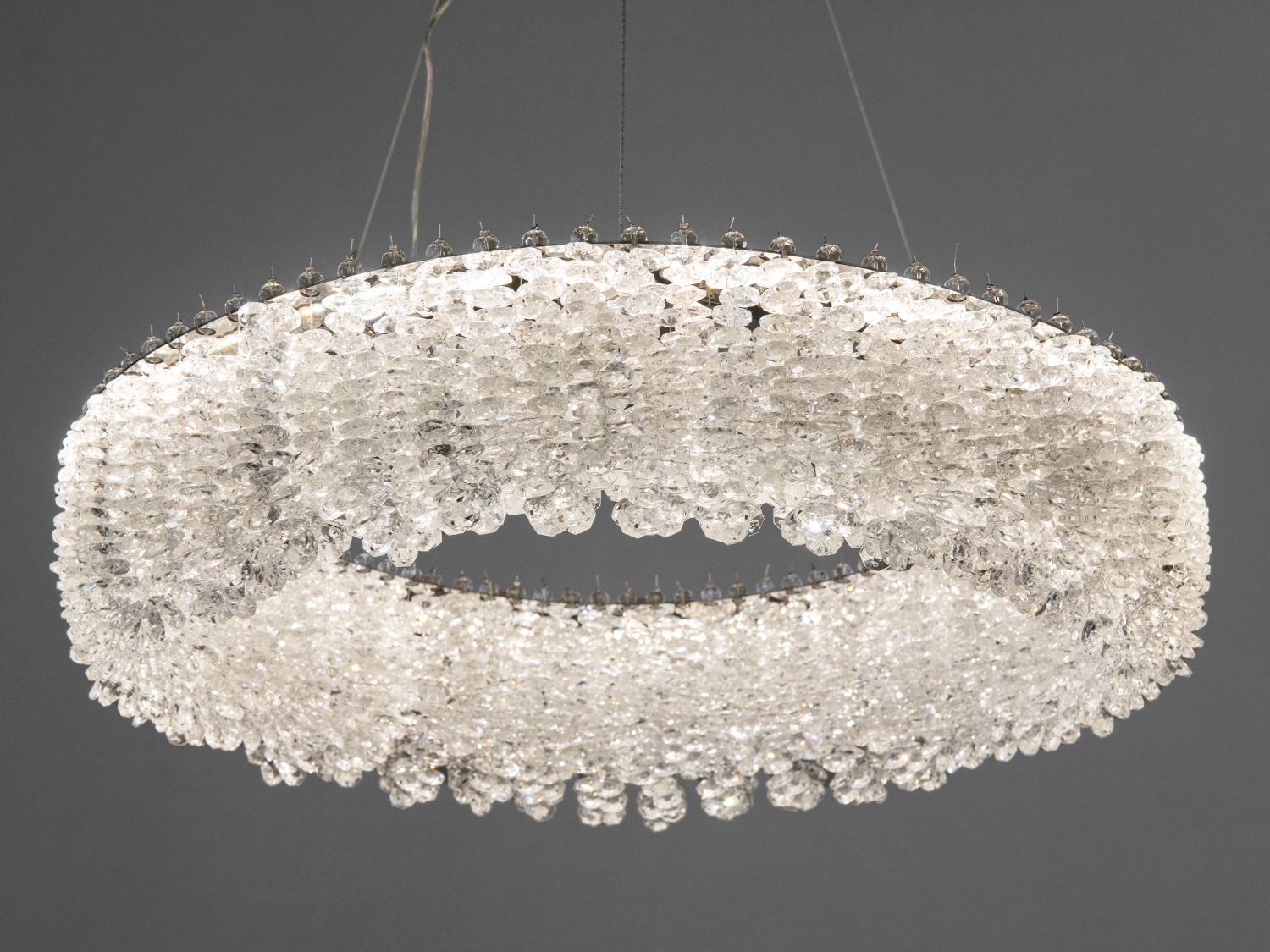 Елегантна люстра з прозорими кришталевими підвісками, що підвішена на тросах. Ідеальна для освітлення великих просторів.