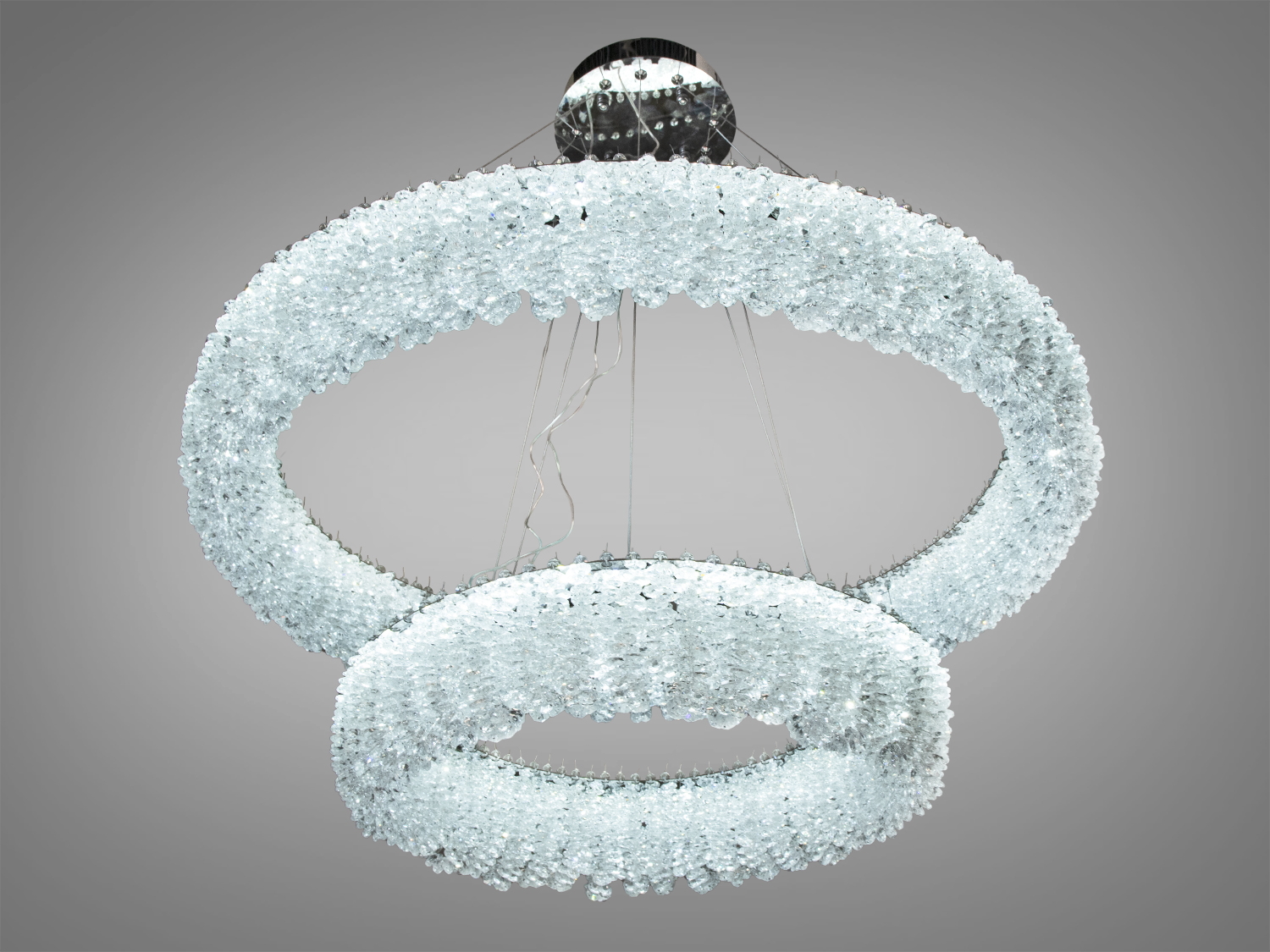 Кругла люстра з прозорими кристалами, підвішена на тонких тросах, підходить для просторих приміщень з високими стелями.