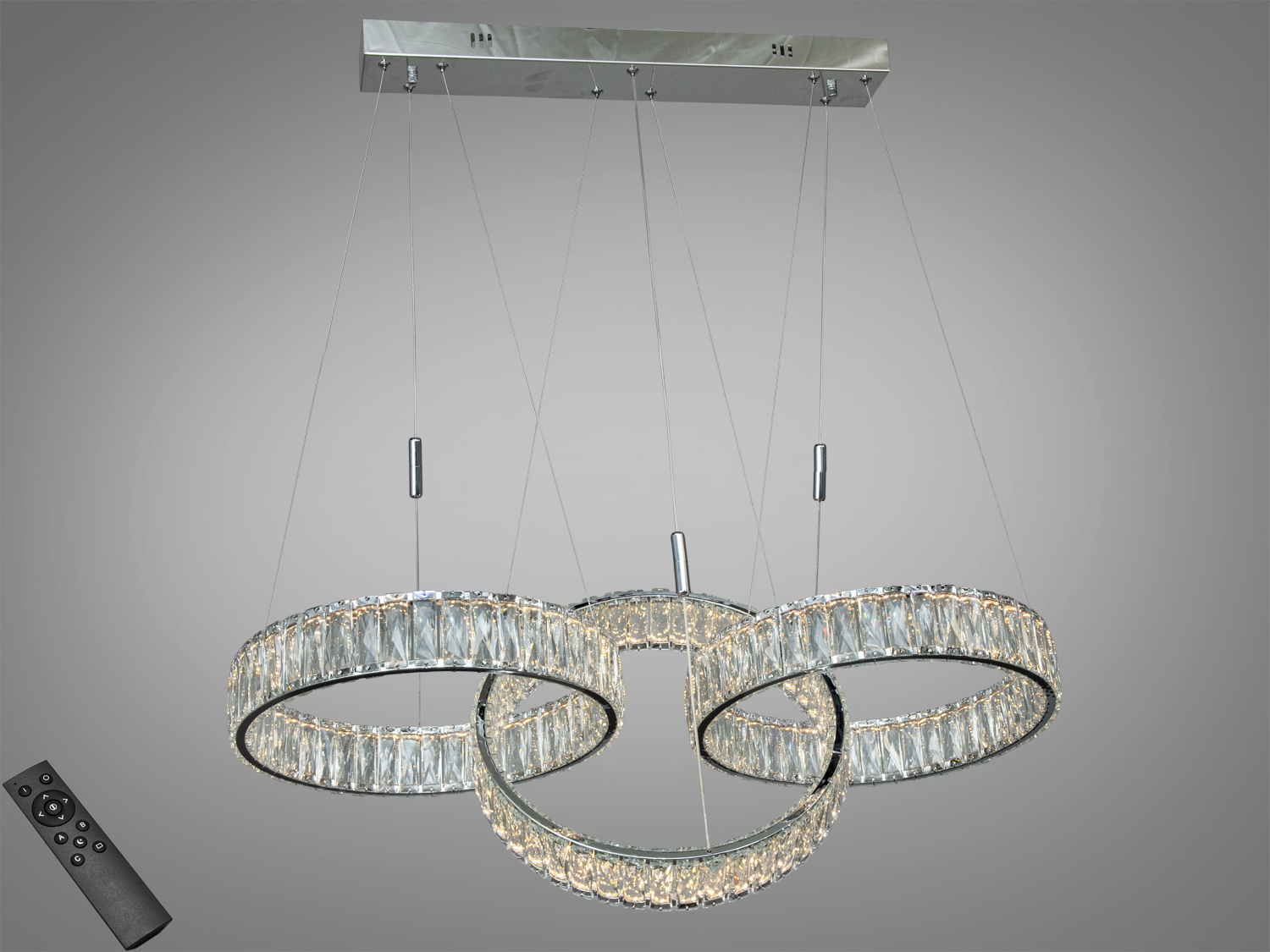 Підвісна люстра з трьома кільцями, оздобленими кришталем, підвішена на металевій основі. Пульт дистанційного керування додає зручності.