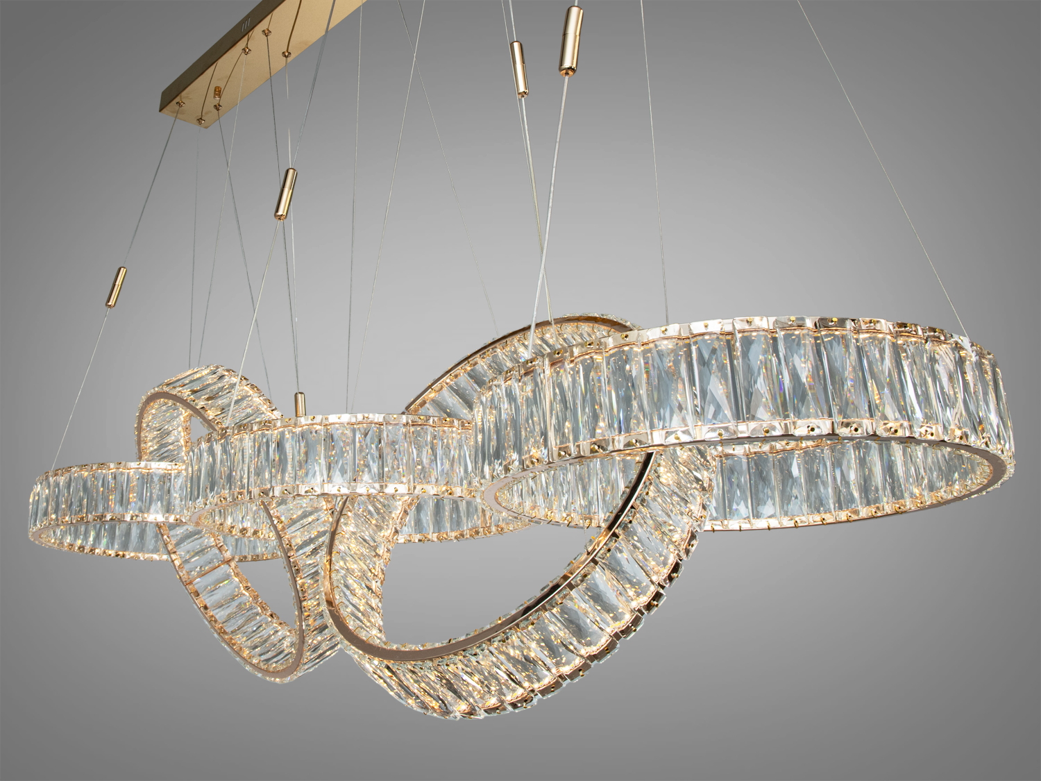 Підвісний світильник з кільцями з прозорого скла, підвішений на кабелях, забезпечує м’яке розсіяне світло. Підходить для віталень.