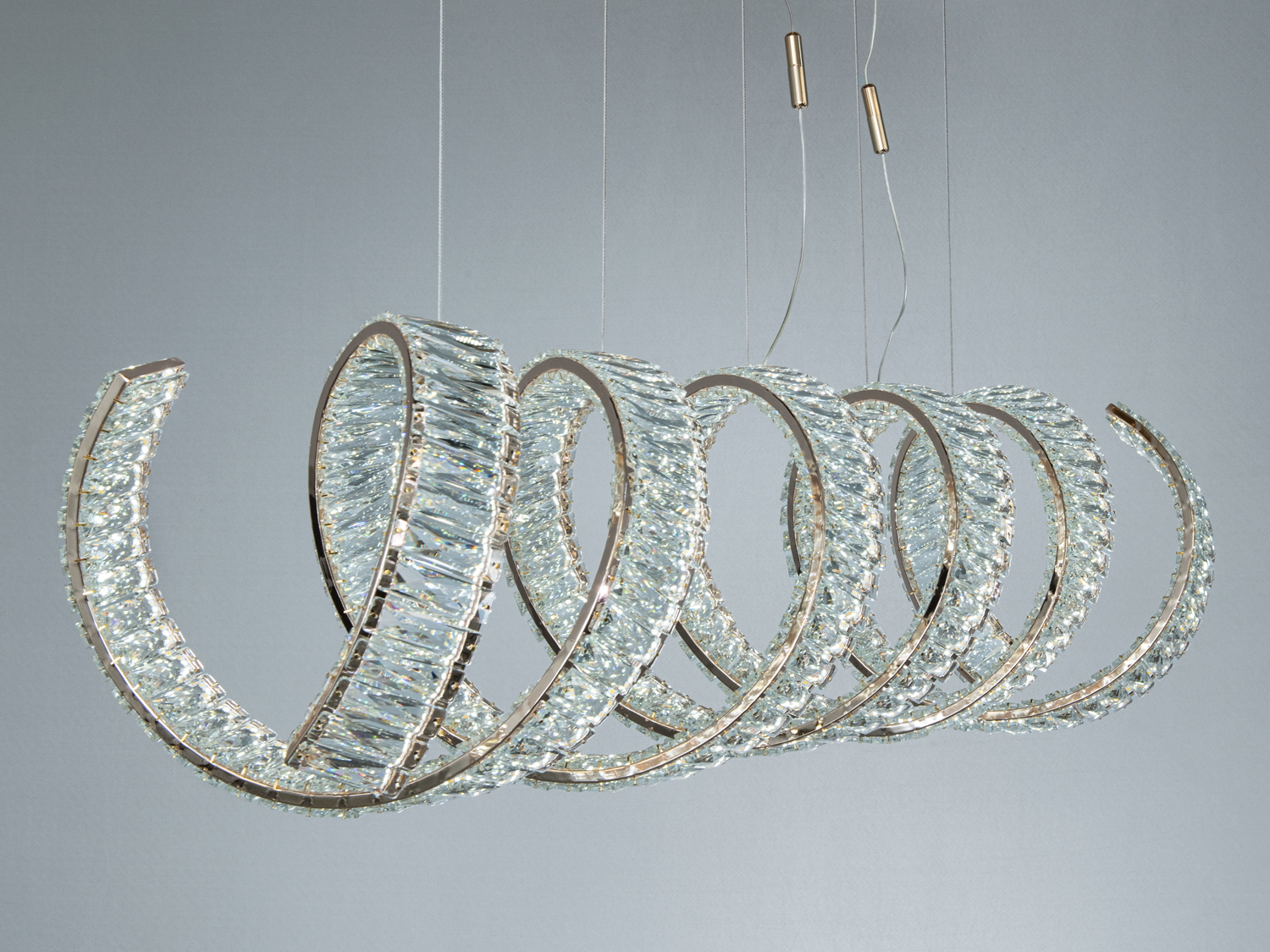 Спіральний світильник з прозорого матеріалу, підвішений на тонких тросах. Підходить для освітлення вітальні.