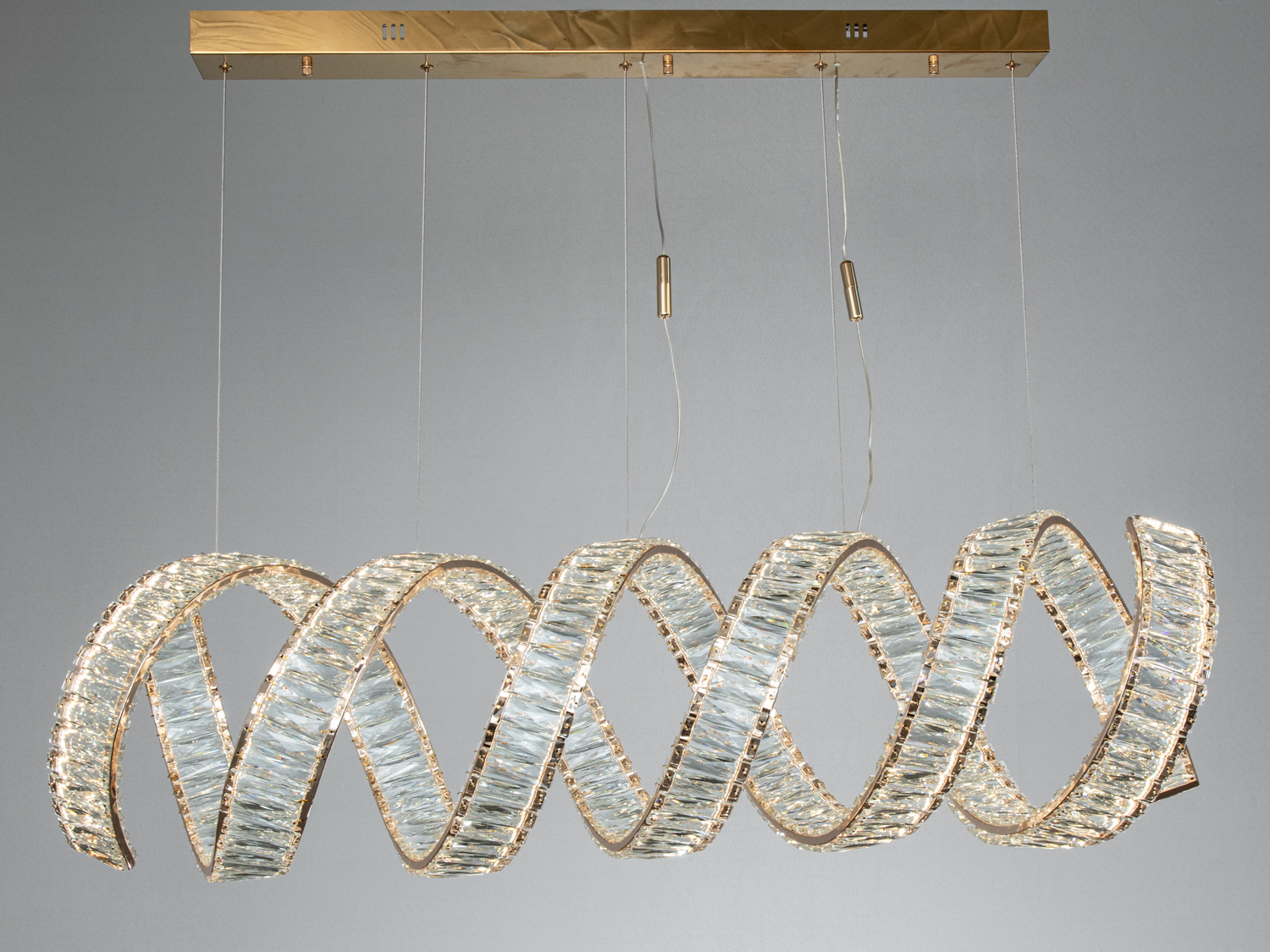 Підвісний світильник із золотистою основою та спіральною формою. Використовується для створення акцентного освітлення.