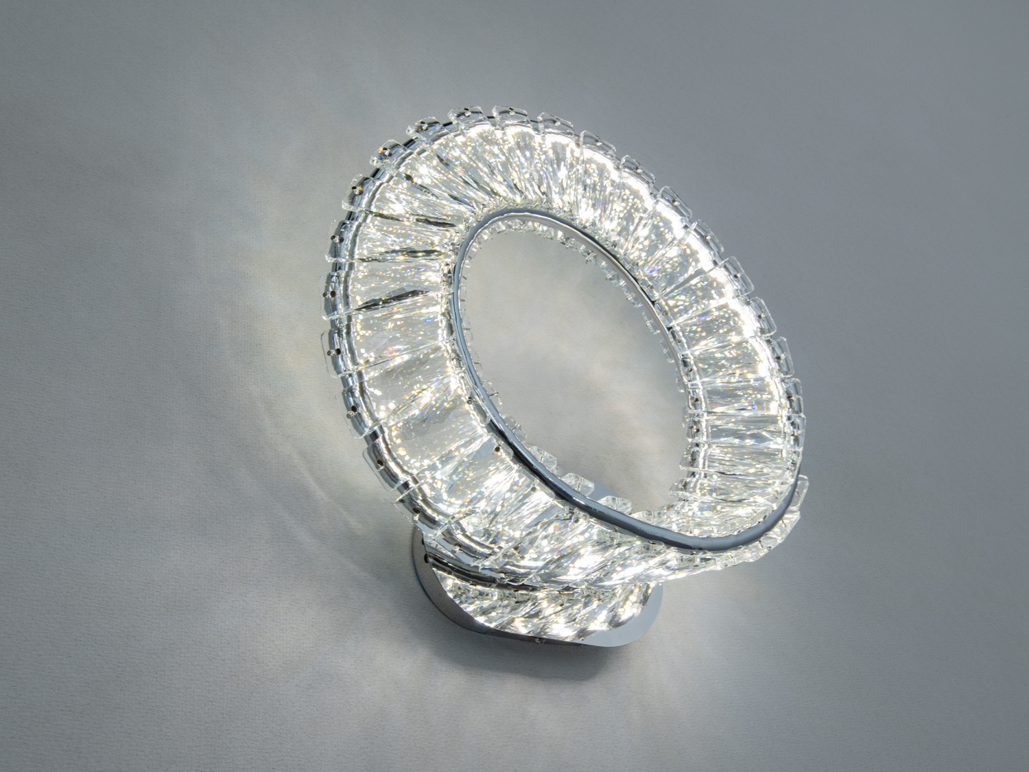 Світильник кільцевої форми з кришталевими деталями, що відбивають світло. Ідеальний для монтажу в вітальні.