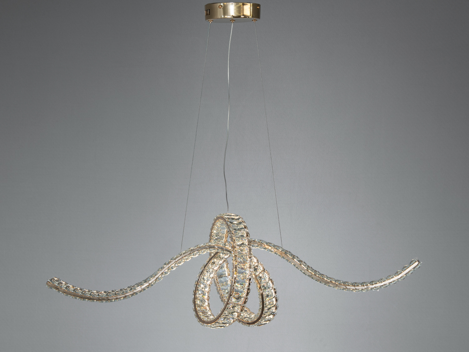 Підвісна люстра зі скляними елементами, що утворюють вигнуті лінії. Підходить для сучасного інтер′єру, створює м’яке освітлення.