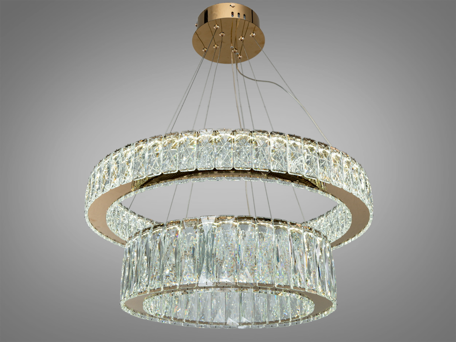 Підвісна люстра з двома кільцями кришталевих елементів, кріпиться на металевій основі. Ідеальна для вітальні або їдальні.