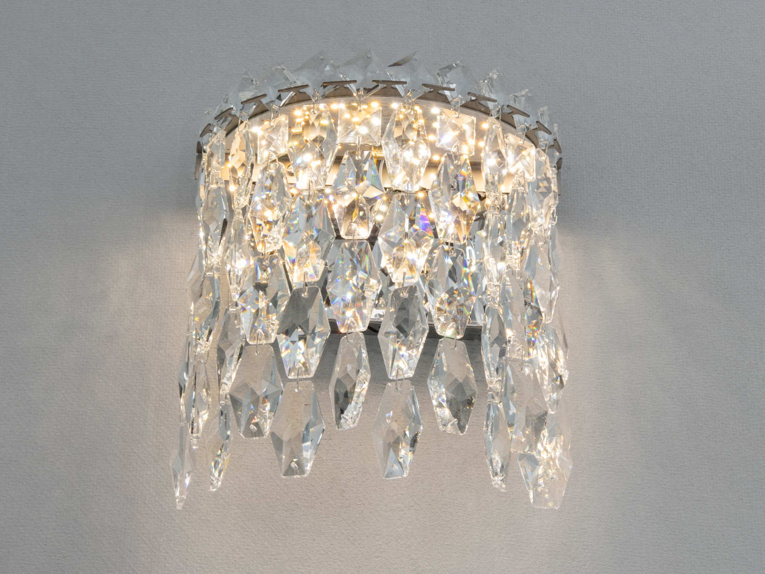 Кришталевий настінний світильник з багатоярусними підвісками, що підкреслює розкішний стиль інтер’єру. Підходить для вітальні.