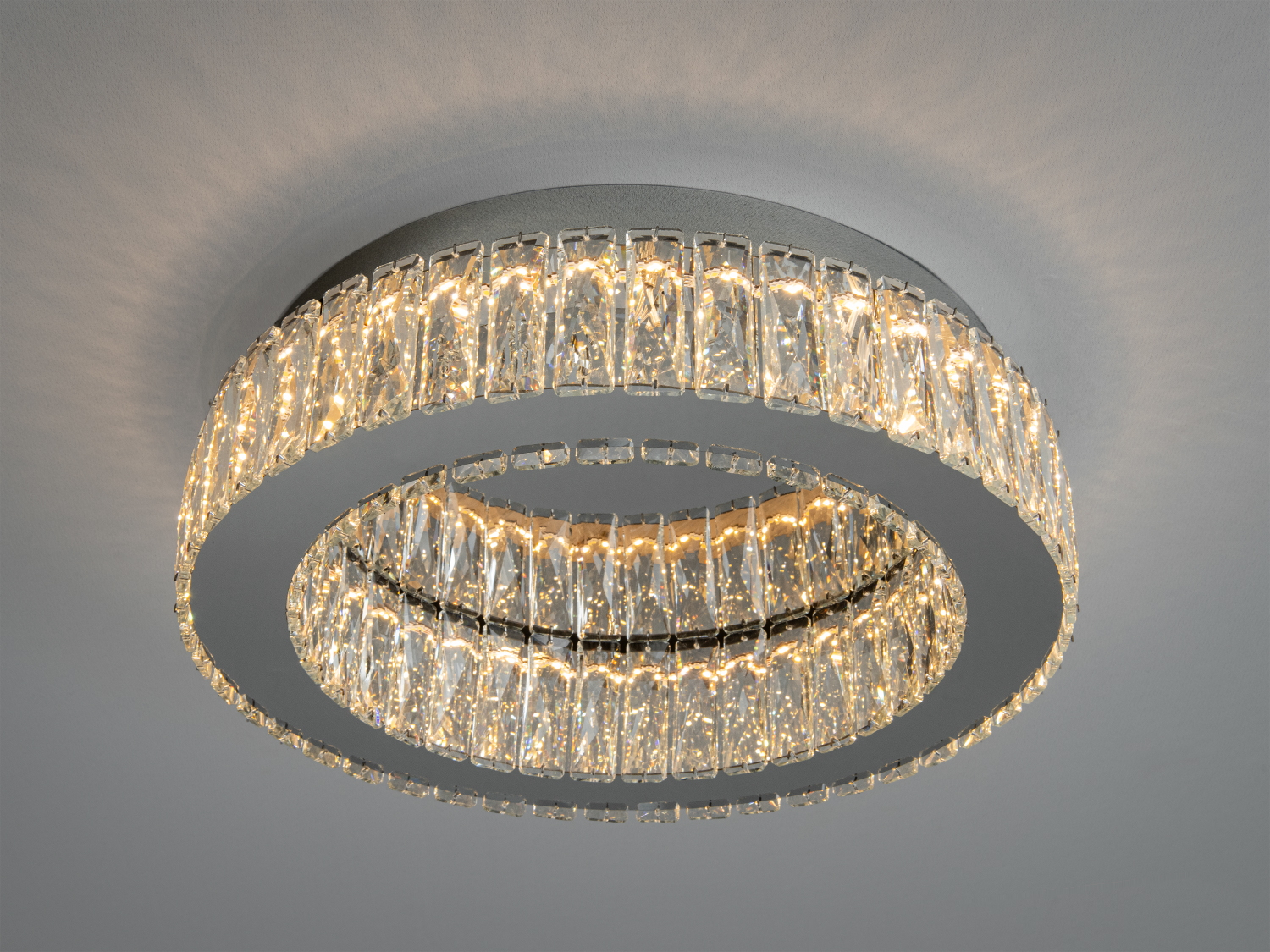 Кругла стельова люстра з кришталевими елементами, що створюють тепле біле світло. Ідеально підходить для сучасного інтер’єру.
