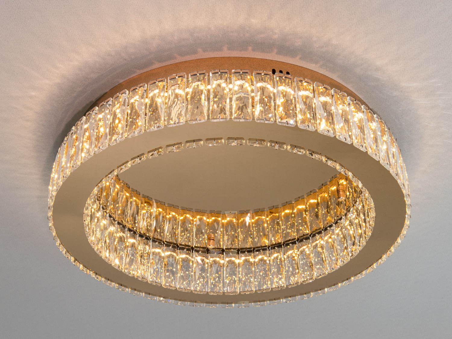 Кругла стельова люстра з кришталевими елементами, які створюють м′яке світло. Призначена для монтажу в сучасних інтер’єрах.