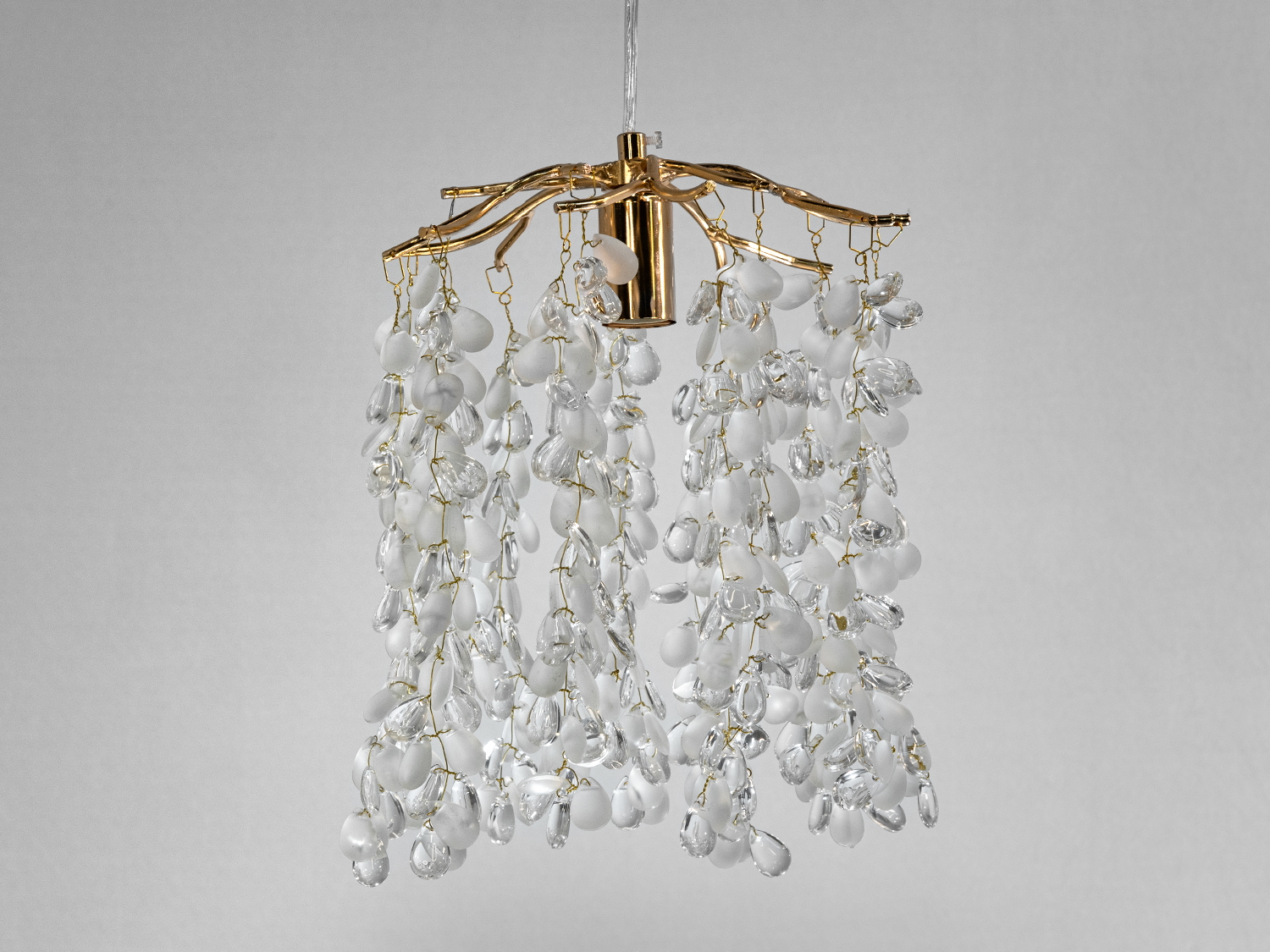 Люстра з каскадними скляними підвісками, що нагадують виноградні грона, на золотистій основі, створює атмосферу розкоші.