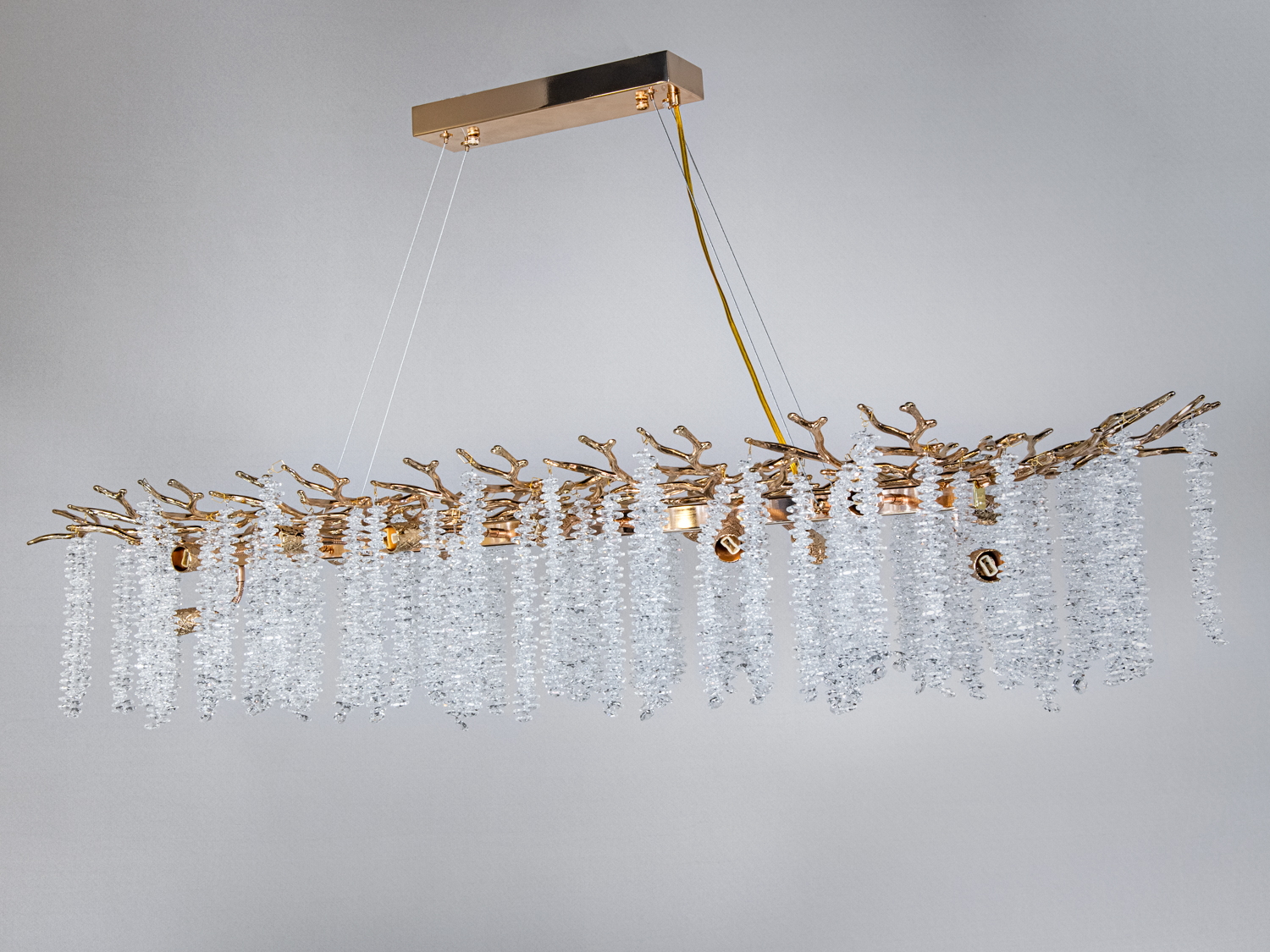 Люстра з кришталевими підвісками, що спадають, на золотистій основі. Підходить для високих стель у вітальні або їдальні.