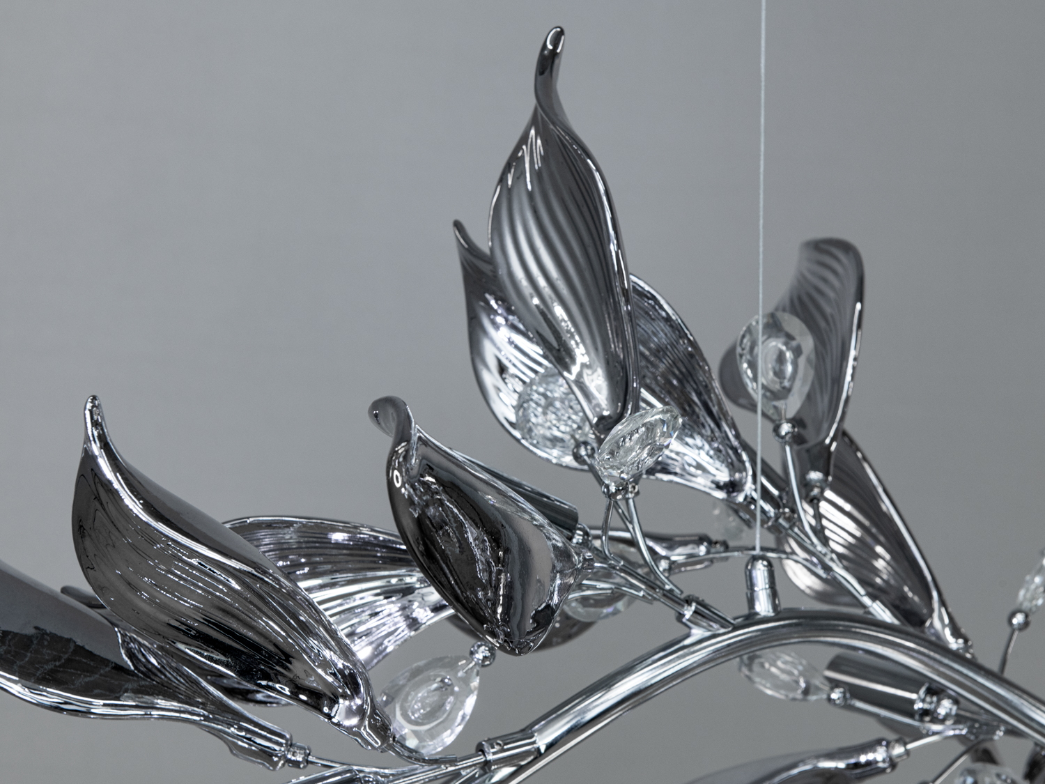 Деталь світильника з текстурованими листками, виготовленими з блискучого матеріалу. Відображає світло, додаючи елегантності.