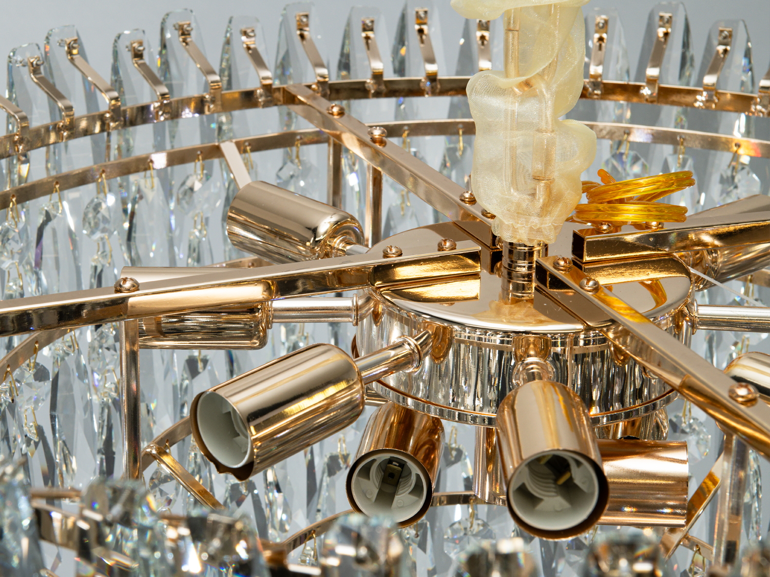 Деталі люстри з золотистим металевим каркасом і кришталевими елементами. Призначена для монтажу на стелю.