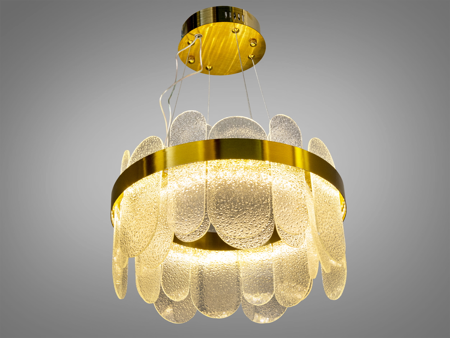 Підвісна люстра з прозорими скляними елементами овальної форми та золотистим обідком, що надає м’яке освітлення для сучасного інтер’єру.