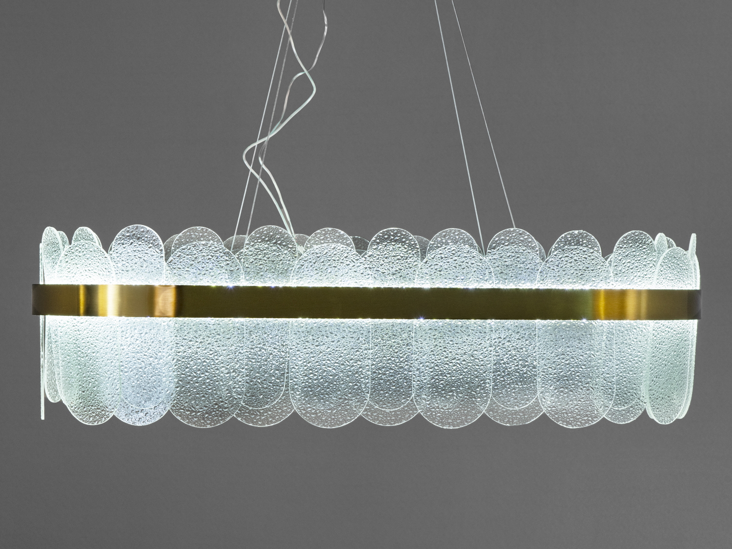 Стильна люстра з овальними скляними елементами та золотистою металевою рамкою, створює м’яке освітлення для сучасного інтер’єру.