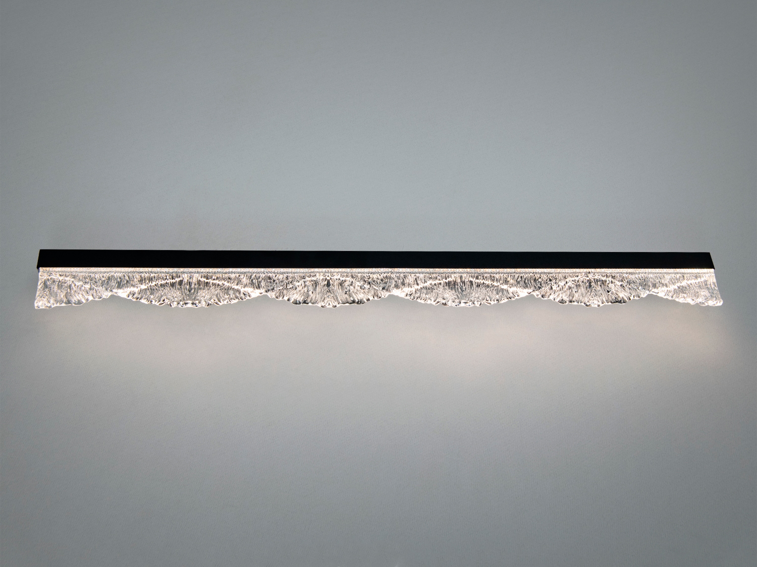 Лінійний світильник з рельєфним скляним дифузором, що створює ефект хвиль. Підходить для настінного монтажу в сучасних інтер’єрах.