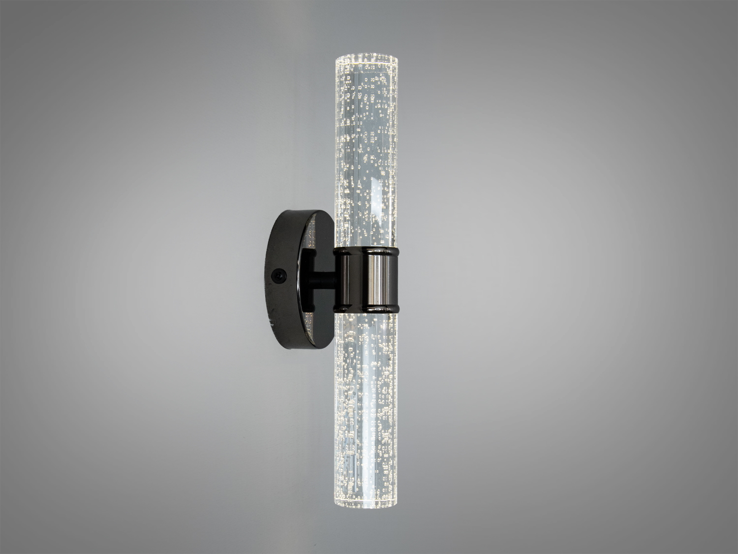 Настінний світильник з прозорим циліндричним корпусом, що містить бульбашки. Монтується на круглу металеву основу, ідеально підходить для сучасного інтер’єру.