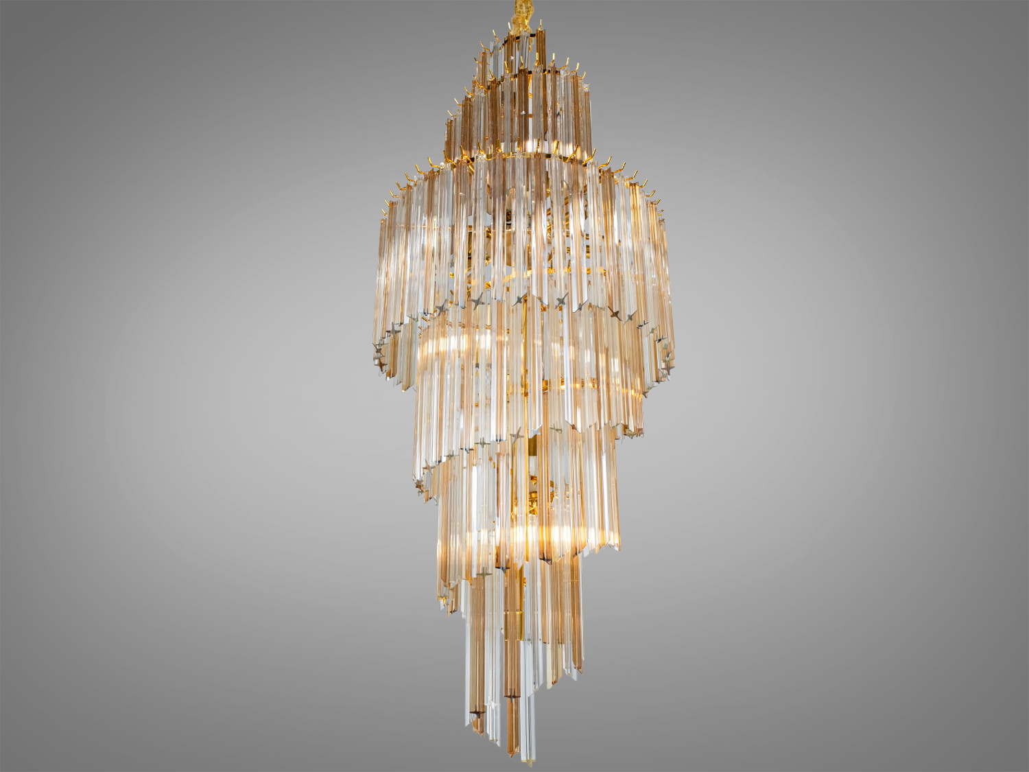 Висока люстра з багатоярусними скляними елементами. Золотистий каркас підкреслює розкіш, підходить для віталень або холів.