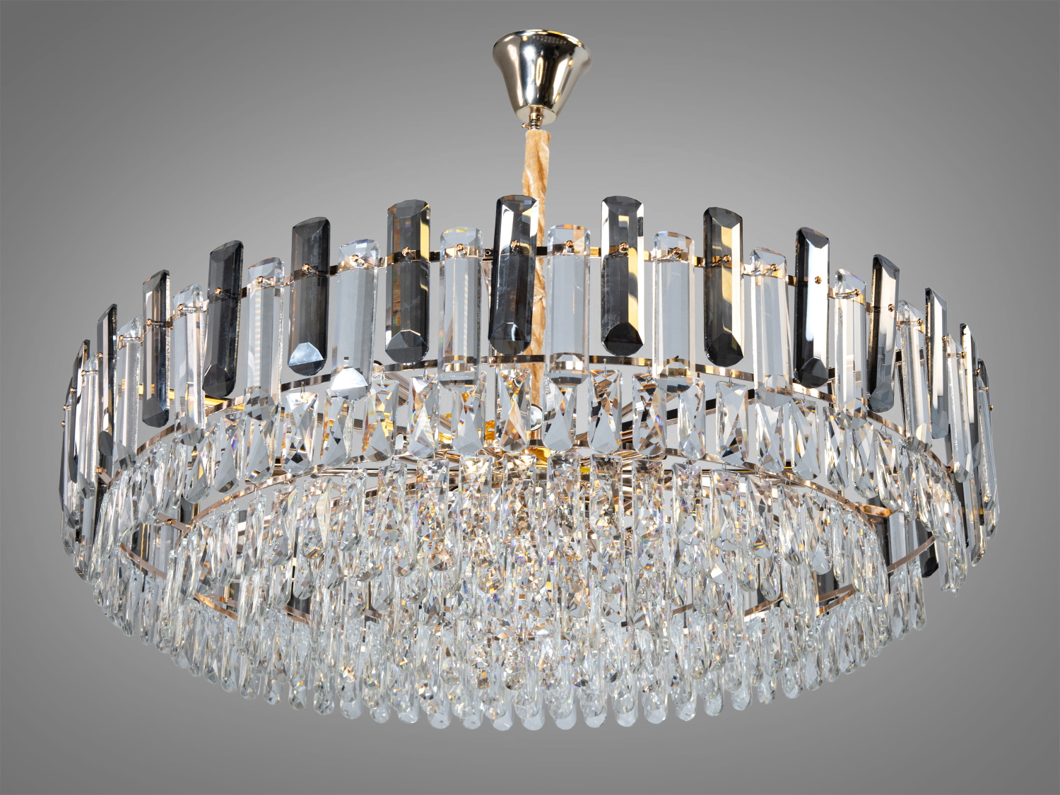 Кругла кришталева люстра з золотим покриттям та вертикальними підвісками для елегантного освітлення вітальні.