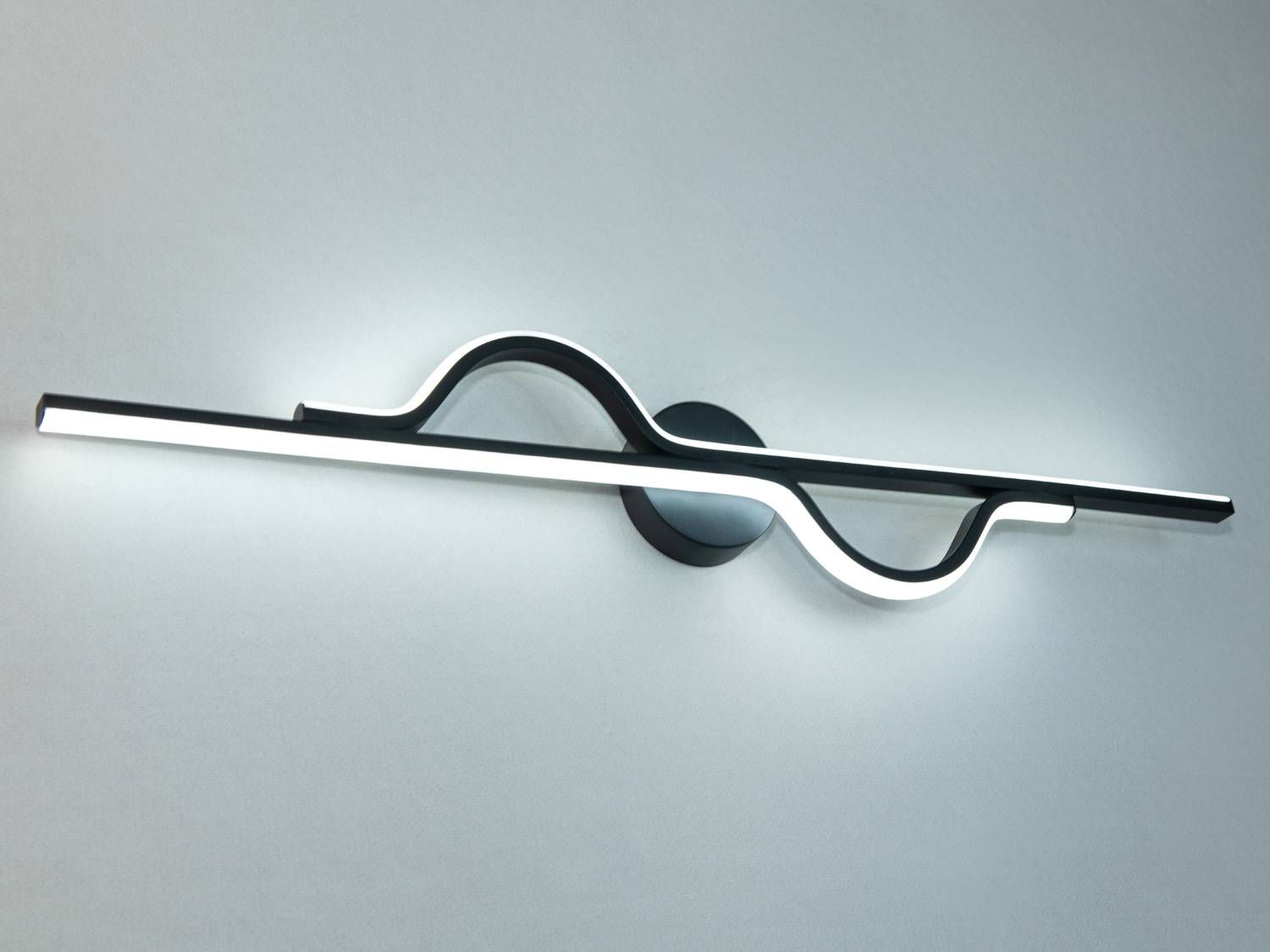 Світлодіодний світильник світить холодним білим кольором світіння та має незвичайну хвилясту форму.