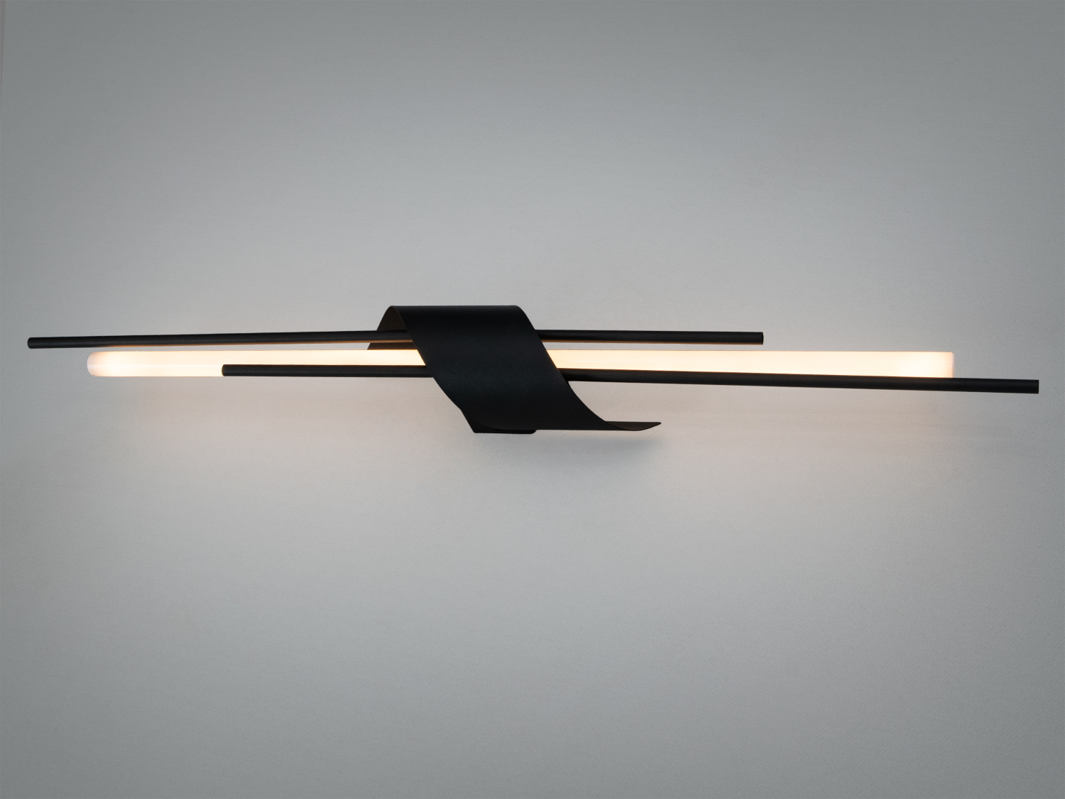 Настінний світильник з чорного металу з двома паралельними трубками, що випромінюють м’яке світло. Ідеально підходить для сучасного інтер’єру.