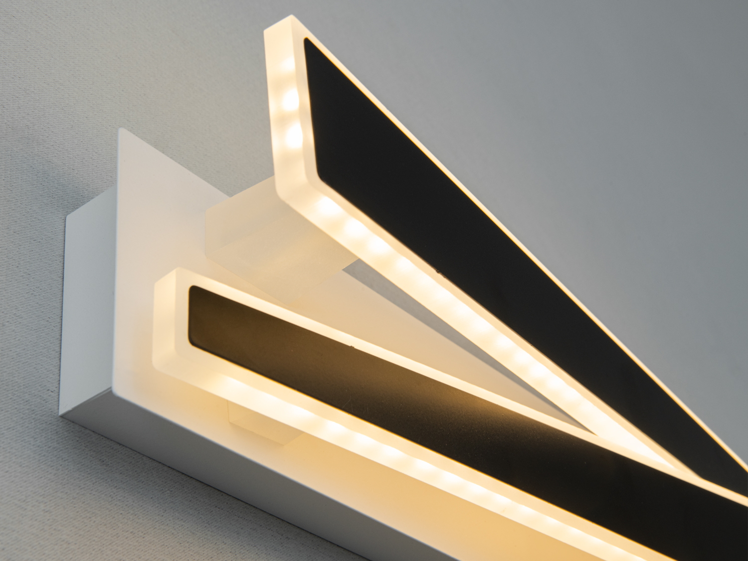 Настінний світильник з теплим LED-світлом, чорні прямокутники з білими рамками, ідеальний для затишного освітлення.