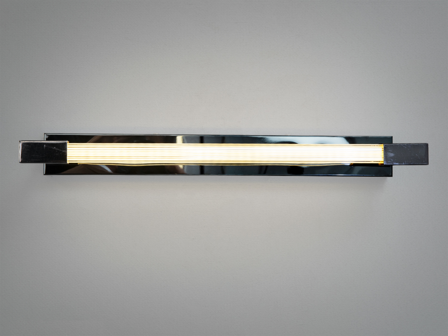 Настінний світильник прямокутної форми з металевим корпусом і теплим світлом, що підходить для сучасного інтер′єру.