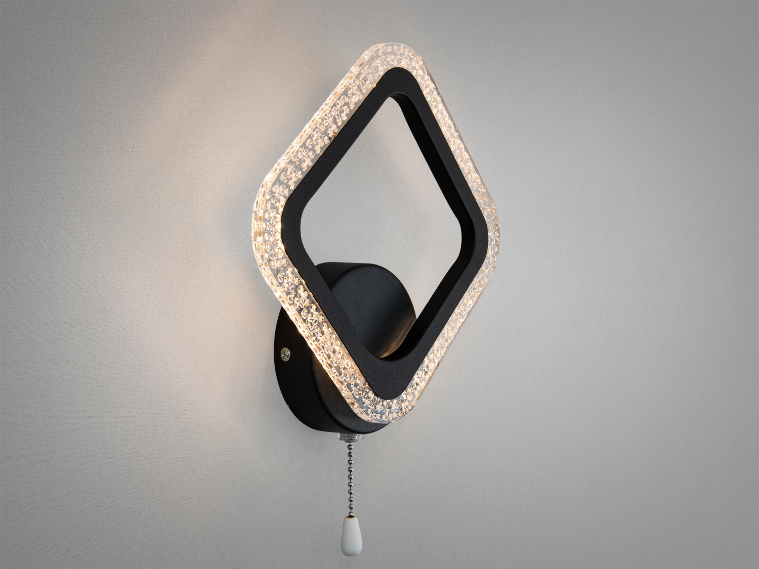 Декоративний світильник з квадратною рамкою, що підсвічується. Виготовлений з чорного металу, має вимикач-ланцюжок для зручності.