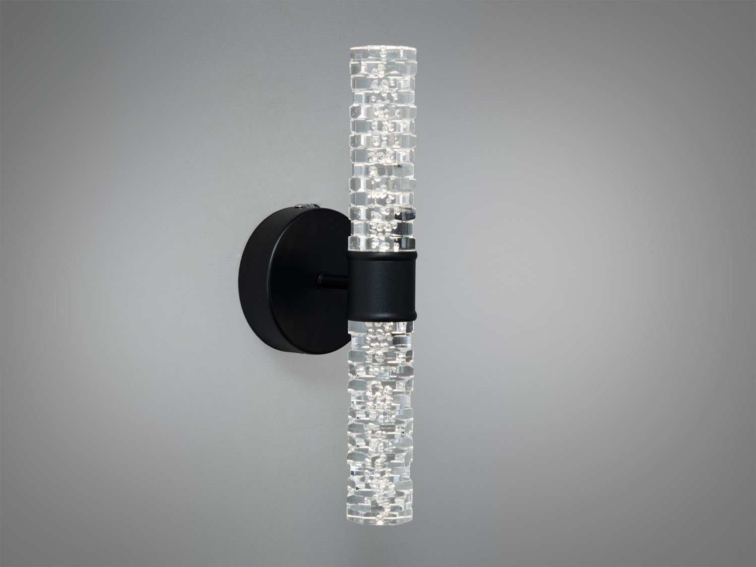 Світильник з прозорим плафоном у формі трубки, закріплений на чорній круглій основі для вертикального монтажу.