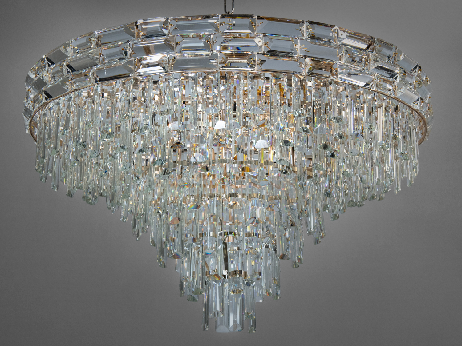 Люстра прикрашена безліччю кришталів різної величини та розмірів, розташованих каскадом, що падають нижче з кожним рівнем. 