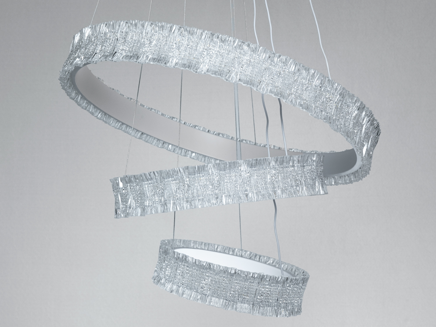 Світильник з трьома спіральними кільцями, підвішеними на тонких дротах. Матеріал має текстуру, що нагадує металеву сітку.