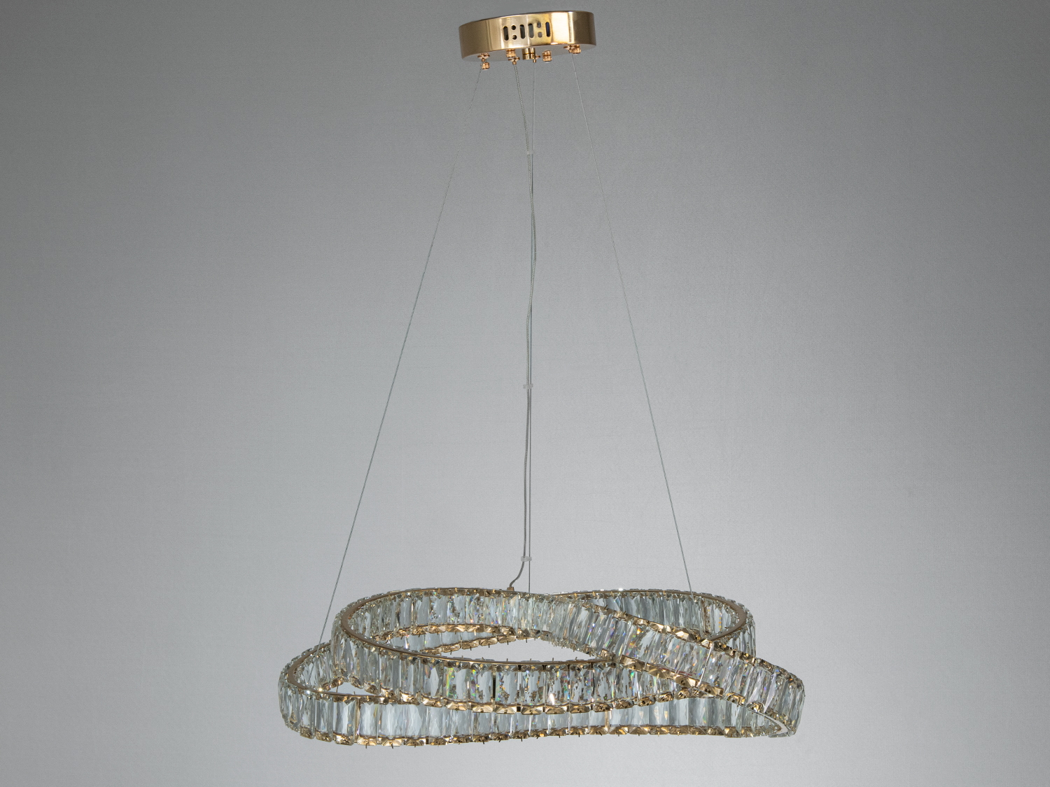 Елегантний світильник з подвійним кільцем кристалів, підвішений на тонких тросах. Підходить для високих стель.
