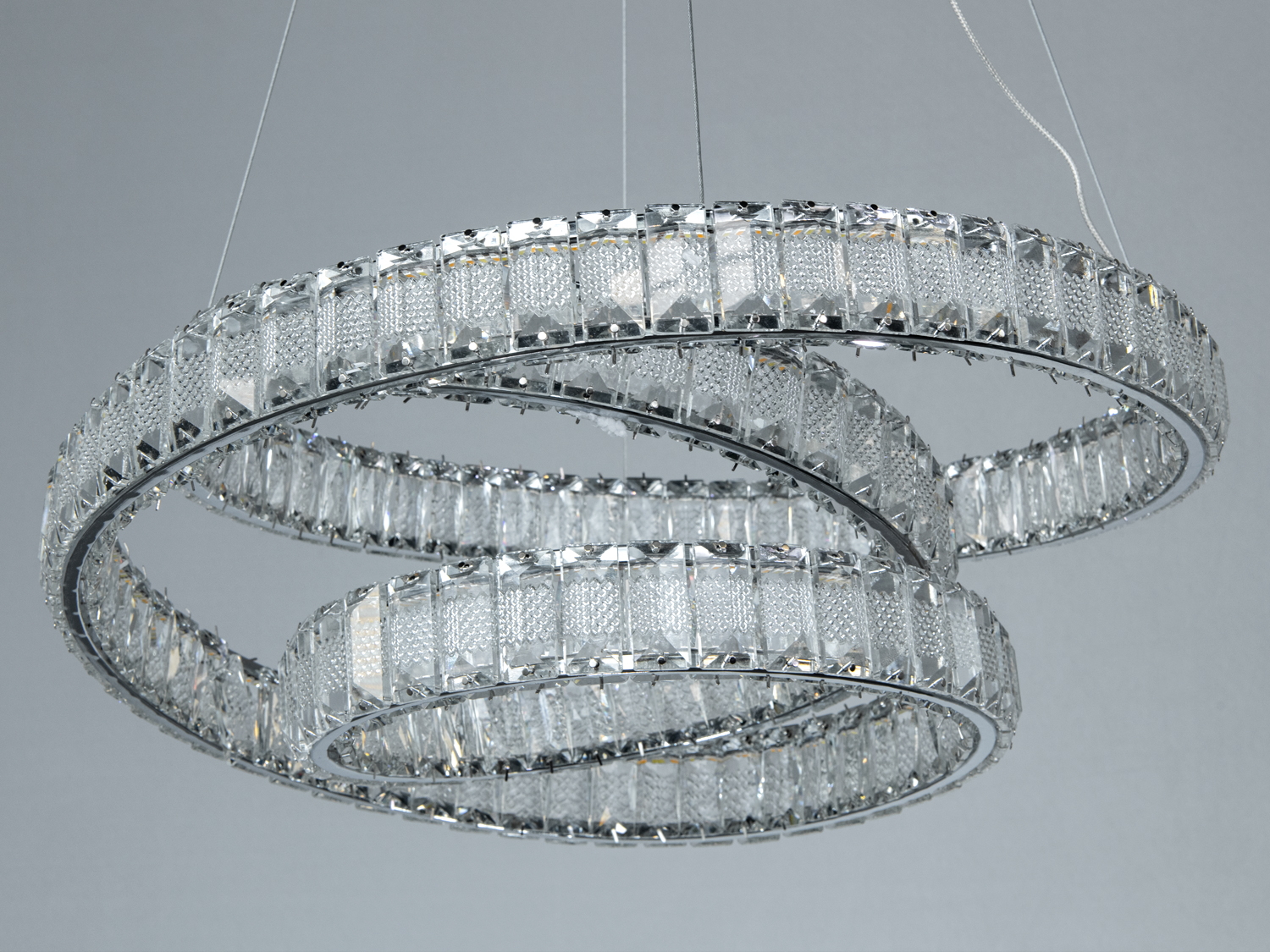 Декоративна люстра з двома кільцями, підвішена на тонких тросах, забезпечує рівномірне освітлення.