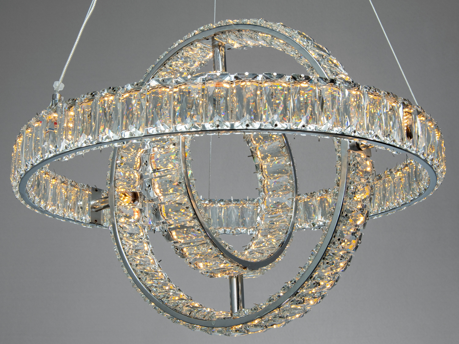Люстра з кришталевими кільцями, що підвішена на тонких тросах. Відмінно підходить для вітальні з високими стелями.