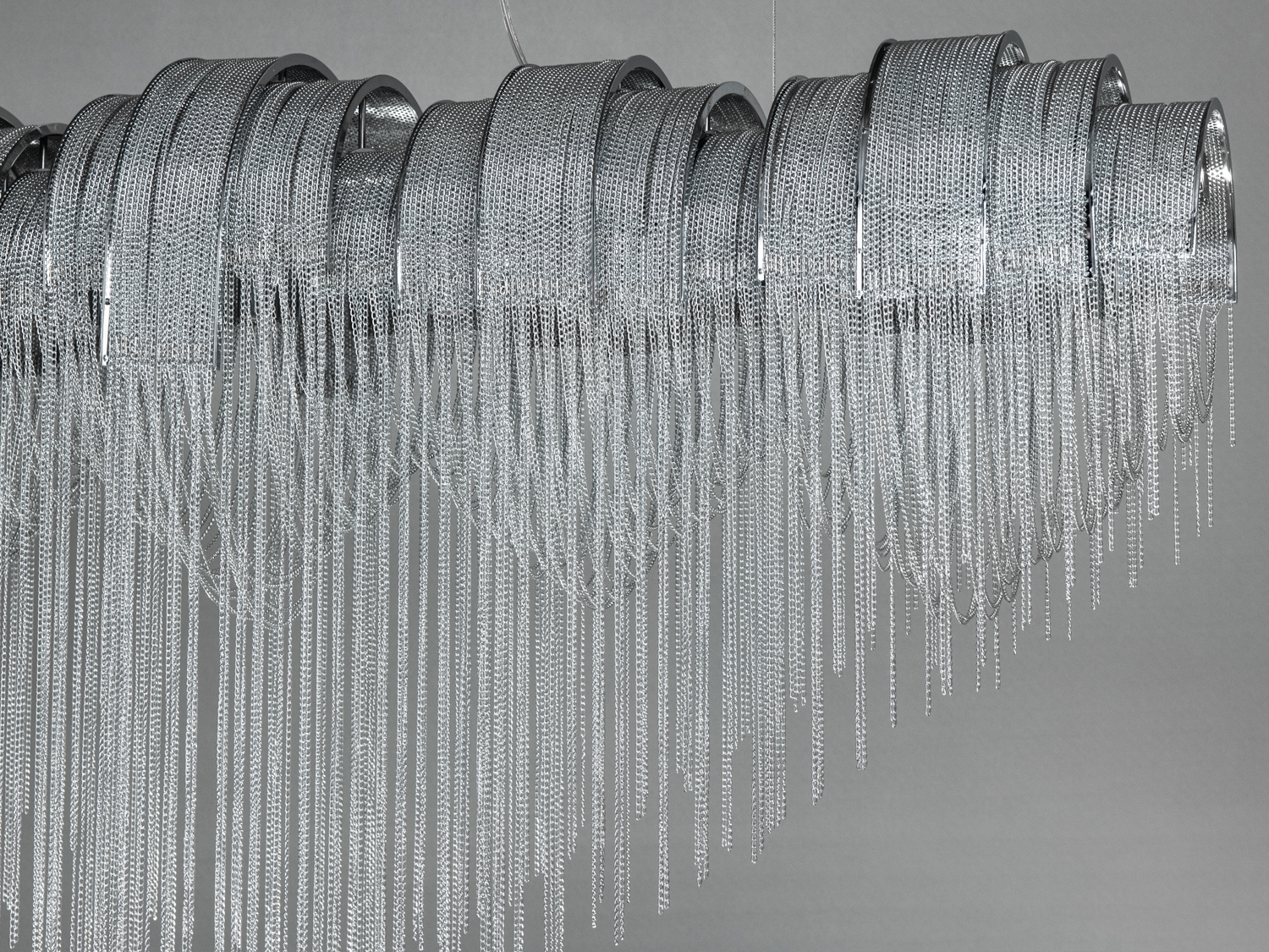 Люстра особливо ефектна в приміщеннях із високими стелями, де її подовжена форма та каскад ланцюгів розкриють свою чарівність повною мірою.