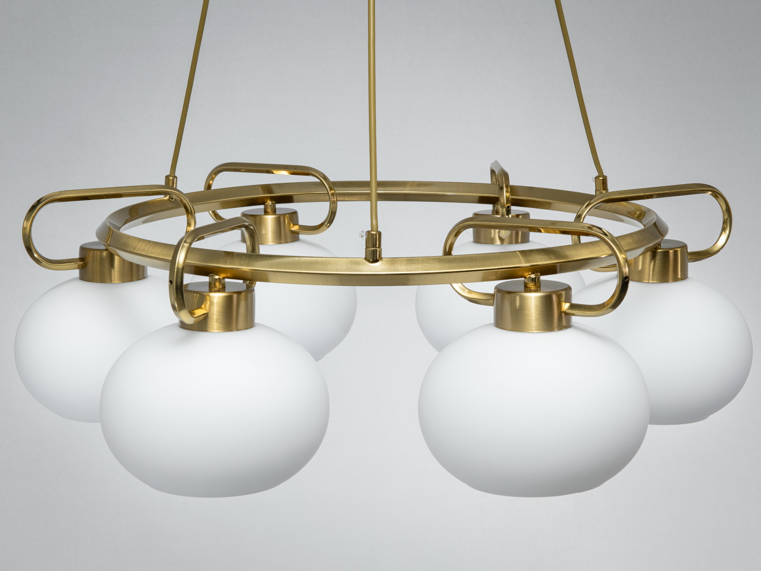 Металева люстра з шістьма круглими плафонами, підвішена на трьох кабелях. Ідеальна для сучасного інтер′єру.