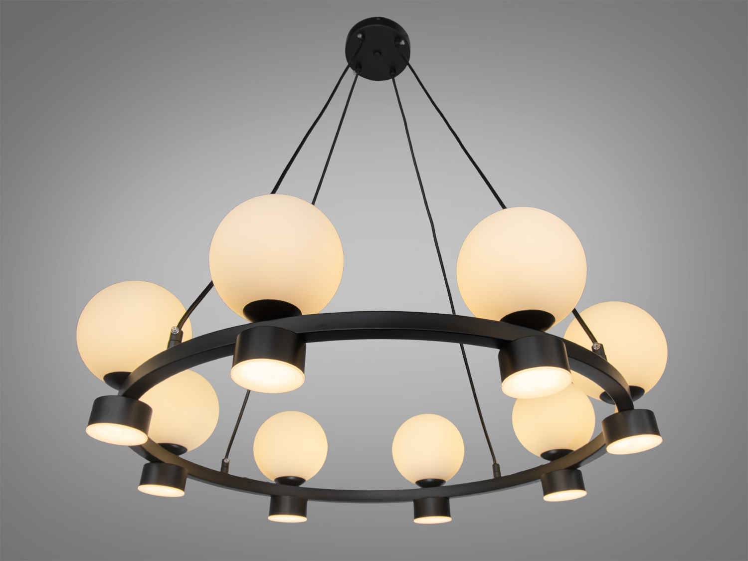Люстра з теплим жовтим світлом, чорний каркас з кулястими плафонами, ідеальна для затишного освітлення вітальні.