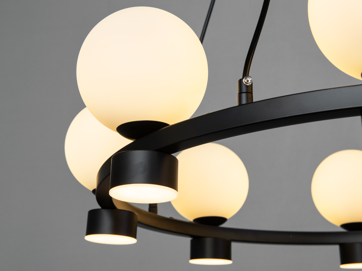 Деталь люстри: чорний металевий обід і кулясті плафони, підвісна конструкція для рівномірного розподілу світла.