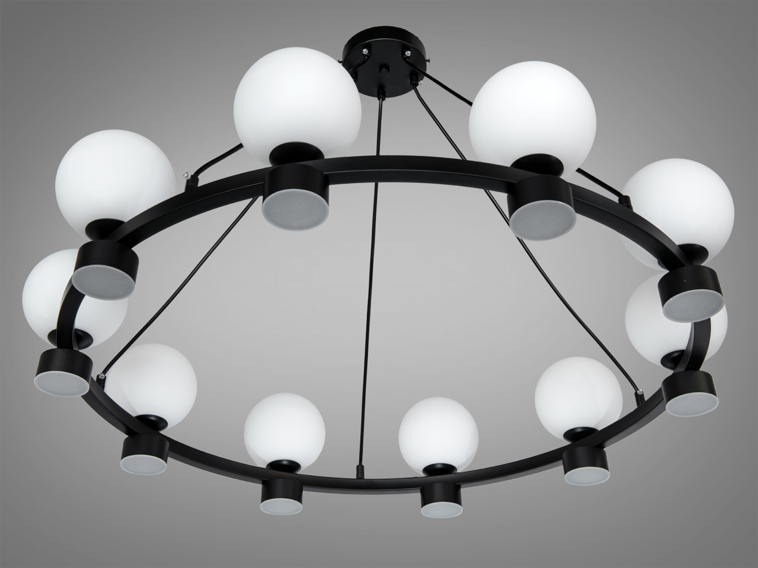 Люстра з білими круглими плафонами, що забезпечують рівномірне освітлення, підвішена на чорній основі.