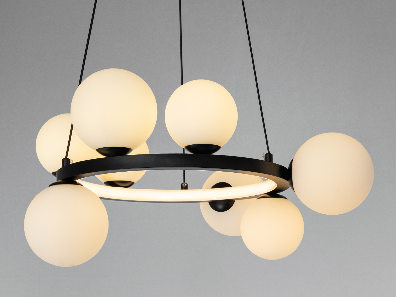 Кільцева люстра з вісімью матовими кулями, що підвішені на чорних тросах, створює стильний акцент у просторі.