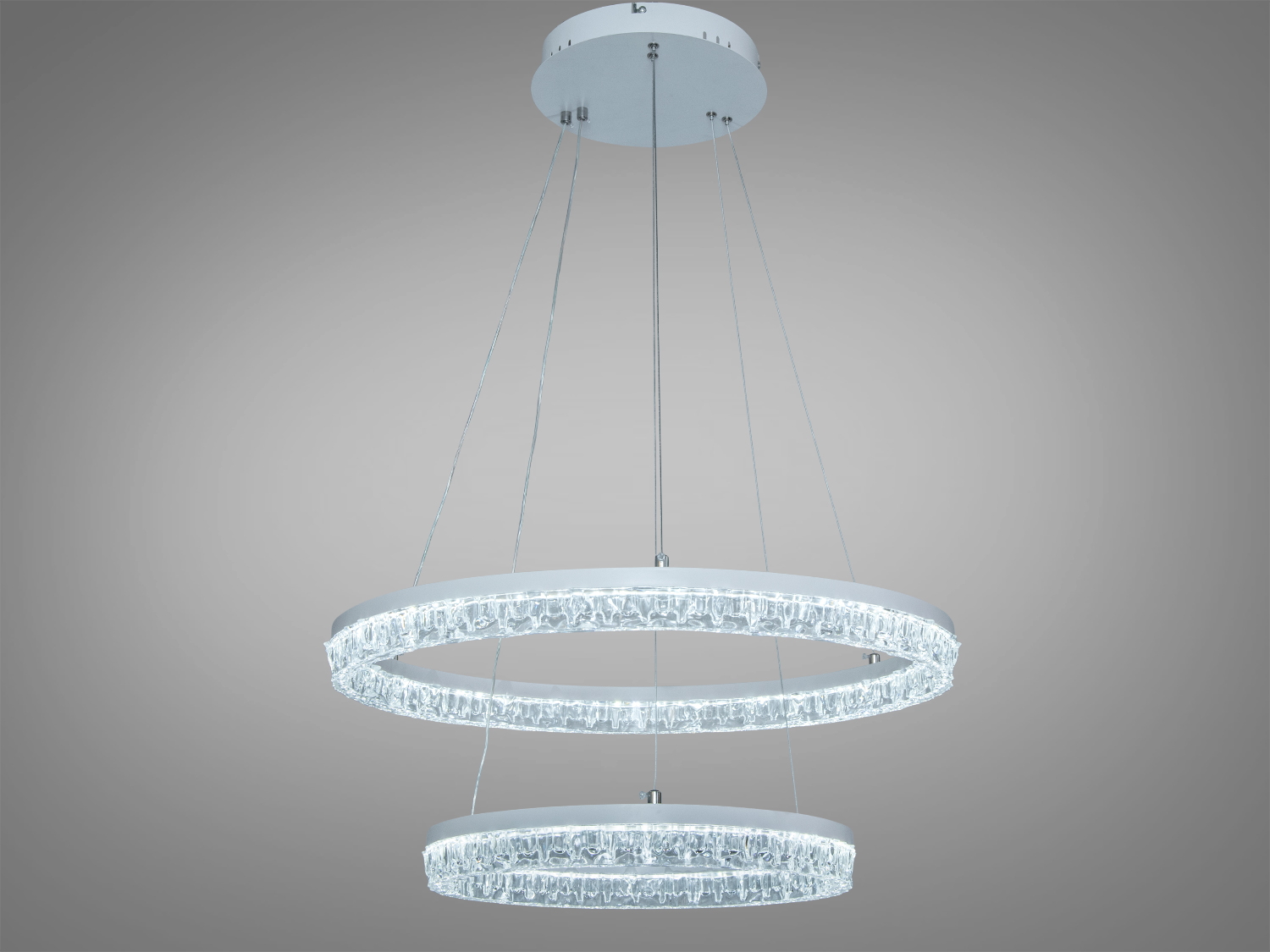 Підвісний світильник з двома круглими LED-кільцями, підвішеними на тонких тросах. Прозорий матеріал забезпечує рівномірне розсіювання світла.