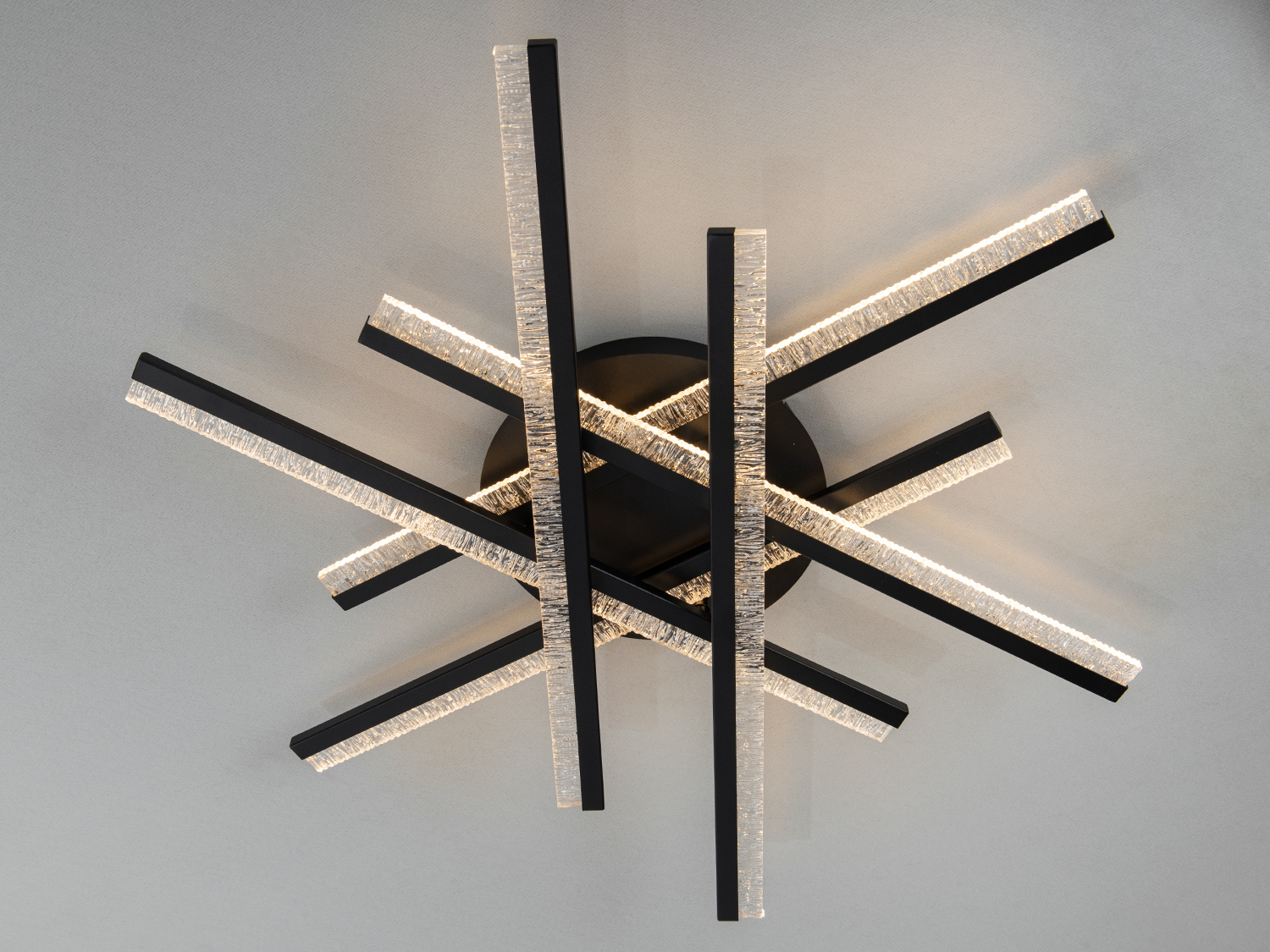 Світильник з чорними лініями, що перетинаються, з прозорими краями, які створюють ефект розсіяного світла. Ідеальний для вітальні.